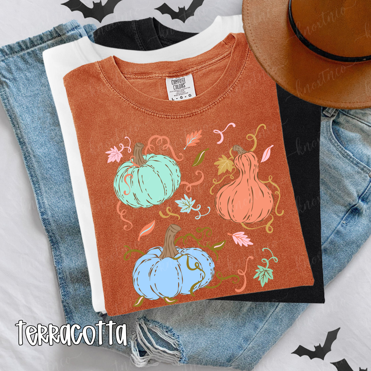 Terracotta Comfort Colors T-shirt featuring three colorful whimsical pumpkins in mint, peach, and light blue with fall leaves and curly vines.
